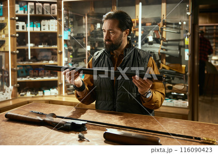 Seller cleaning gun with ramrod while working in hunting shop Seller cleaning gun with ramrod while working in hunting shop 116090423