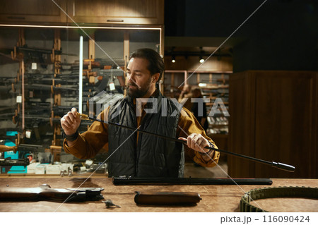 Weapon shop owner cleaning gun with brush preparing goods for sale Weapon shop owner cleaning gun with brush preparing goods for sale 116090424