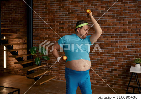 Fat man doing sport training with dumbbells at home 116090488