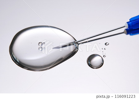 A drop of medicine flowing from a syringe with a needle. 116091223