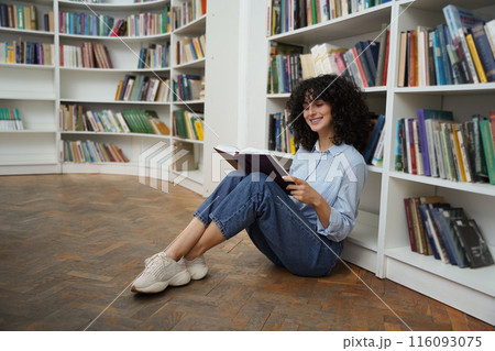 Dark-haired woman sitting on the floor with a book in hands 116093075