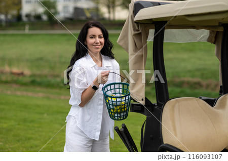 Beautiful golfer posing near her transport on the green field Beautiful golfer posing near her transport on the green field 116093107