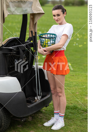 Beautiful golfer posing near her transport on the green field Beautiful golfer posing near her transport on the green field 116093115