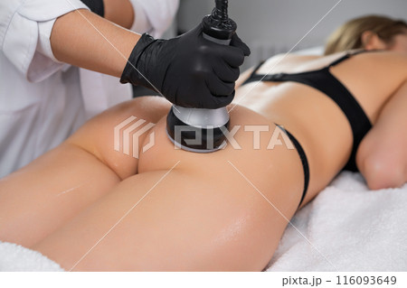 Young women undergo body contouring via ultrasound cavitation at a beauty salon. Close up woman buttocks Young women undergo body contouring via ultrasound cavitation at a beauty salon. Close up woman buttocks 116093649