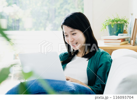 リビングでパソコンを使う若い女性 116093704