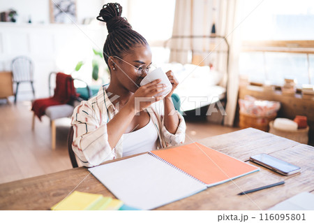 Black woman drinking coffee from mug at home Black woman drinking coffee from mug at home 116095801