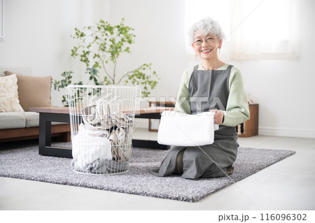 リビングで洗濯のタオルを畳むシニア(高齢者)女性 全身 リビングで洗濯のタオルを畳むシニア(高齢者)女性 全身 116096302