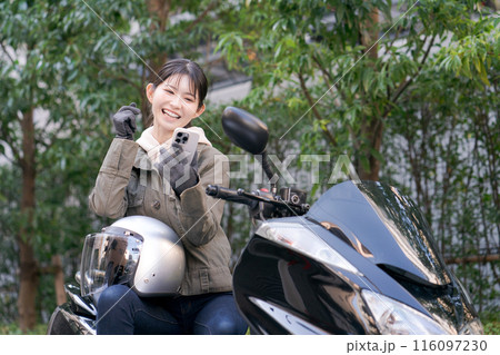 スマホを見て笑顔の女性ライダー 116097230