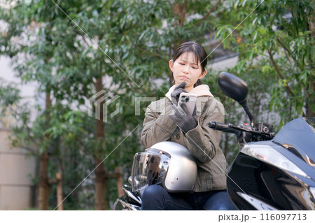 バイクに乗ってスマホを見る女性 バイクに乗ってスマホを見る女性 116097713