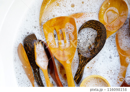 Wooden kitchenware in water and bubbles of dishwashing liquid Wooden kitchenware in water and bubbles of dishwashing liquid 116098158