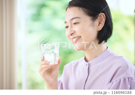 リビングで水を飲む笑顔のミドル女性 116098188