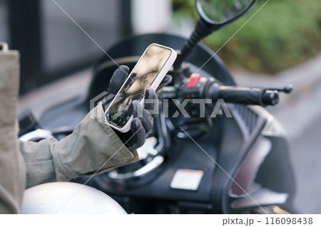 スマホを操作するバイクに乗った女性 116098438