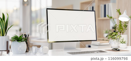 A computer desk featuring a computer mockup, books, headphones, and decorative plants. 116099798