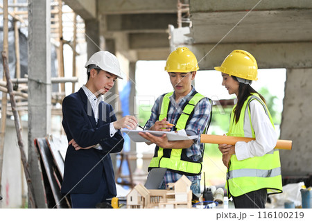 Engineers team and businessman wearing safety helmet reviewing blueprints at building site Engineers team and businessman wearing safety helmet reviewing blueprints at building site 116100219