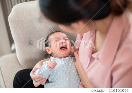 An adorable infant baby son is crying in his mother arms, feeling uncomfortable or hungry. 116101093