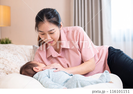 A beautiful young Asian mom is comforting and putting her newborn baby son to sleep in the bedroom. A beautiful young Asian mom is comforting and putting her newborn baby son to sleep in the bedroom. 116101151
