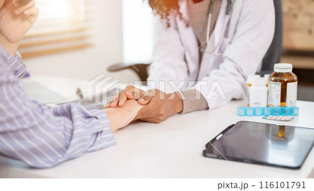 A close-up image of a caring female doctor holding a patient's hand to comfort and reassure them. 116101791