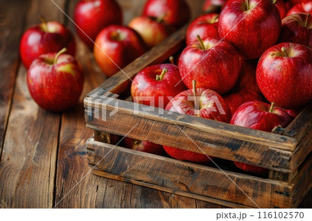Red apples in a crate on rustic wood table. 116102570