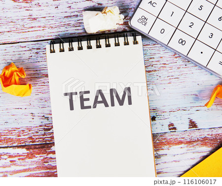 Together Everyone Achieves More. TEAM Concept. TEAM in a notebook next to a calculator and crumpled stickers on the boards 116106017