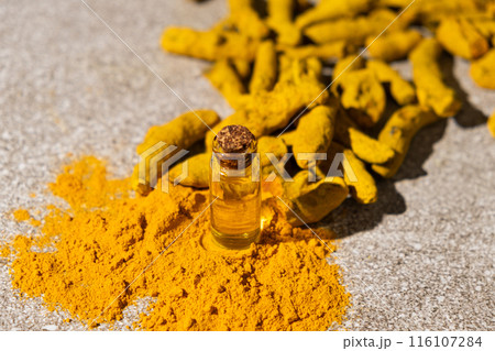 Natural Turmeric Oil in a Glass Bottle with Ground Turmeric Powder and Dry Turmeric Root. 116107284