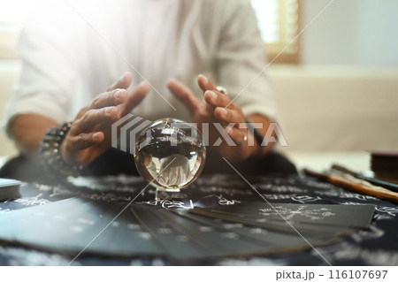 Hands of astrologists around glowing crystal ball. Forecasting and divination concept Hands of astrologists around glowing crystal ball. Forecasting and divination concept 116107697