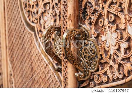 carved wooden door with a traditional oriental Uzbek islamic pattern with bronze handles 116107947
