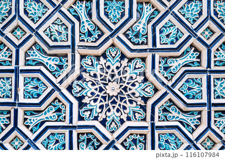 uzbek tile mosaic with traditional oriental Arabic Islamic pattern decorated with blue and white ornament in wall in Uzbekistan 116107984