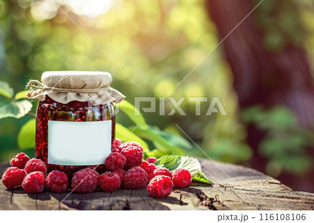 Homemade Raspberry Jam in Glass Jar Surrounded by Fresh Berries and Green Leaves Homemade Raspberry Jam in Glass Jar Surrounded by Fresh Berries and Green Leaves 116108106