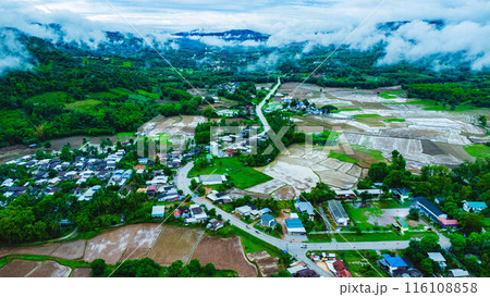 Aerial view of a beautiful rural village landscape in the middle of a nature valley during the rainy season and a stunning view of a flowing river in Loei Province, Thailand. Aerial view of a beautiful rural village landscape in the middle of a nature valley during the rainy season and a stunning view of a flowing river in Loei Province, Thailand. 116108858