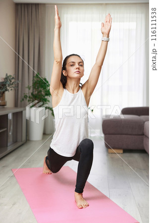 fit woman in sportwear exercising at home, stretching legs. 116111538
