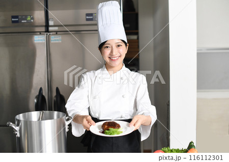 肉料理を提供する若いアジア人の女性調理師 肉料理を提供する若いアジア人の女性調理師 116112301