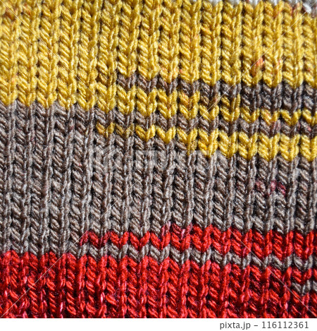 Handmade knitted fabric red yellow and beige wool background texture 116112361