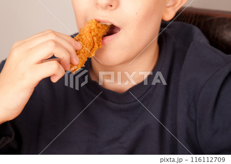 Caucasian man eating fried chicken wings, American fast food culture, cooked chicken pieces Caucasian man eating fried chicken wings, American fast food culture, cooked chicken pieces 116112709