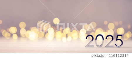 Metal numbers 2025 on a white table with Christmas trees and bokeh lights. Happy New Year 2025 is coming concept. 116112814
