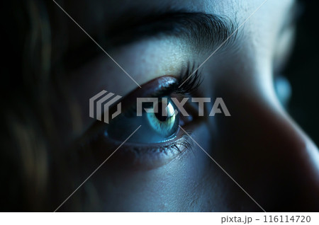 暗闇の中で明るい画面を見つめる女性の目 116114720
