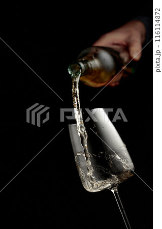 Pouring white wine in a glass goblet. 116114872