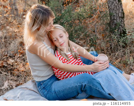 Mother sitting on plaid with her beautiful daughter outdoor in forest with sunshine. Mother sitting on plaid with her beautiful daughter outdoor in forest with sunshine. 116114955