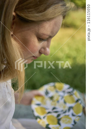 a beautiful young artist in a white dress paints a picture on the river bank 116115050