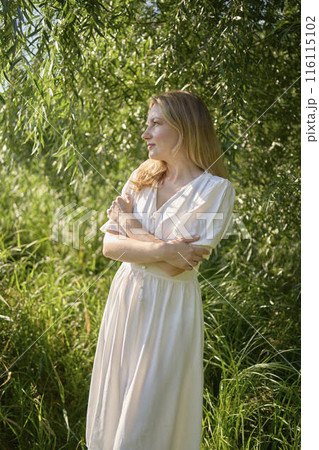 beautiful young artist in a white dress among the trees on the river bank 116115102