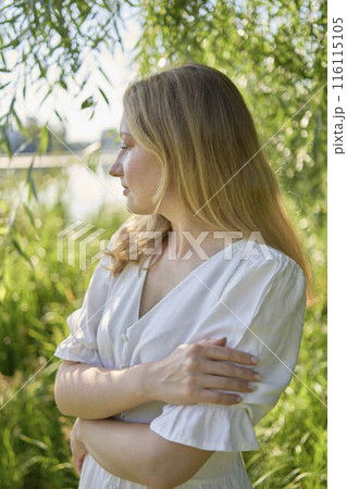 beautiful young artist in a white dress among the trees on the river bank 116115105