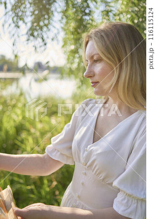 beautiful young artist in a white dress among the trees on the river bank 116115124
