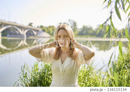 beautiful young artist in a white dress among the trees on the river bank beautiful young artist in a white dress among the trees on the river bank 116115134