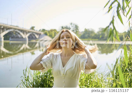 beautiful young artist in a white dress among the trees on the river bank beautiful young artist in a white dress among the trees on the river bank 116115137