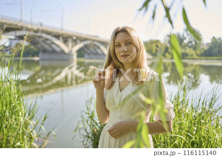 beautiful young artist in a white dress among the trees on the river bank 116115140