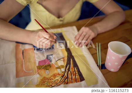 a beautiful young artist in a yellow dress paints a customized shopping bag a beautiful young artist in a yellow dress paints a customized shopping bag 116115273