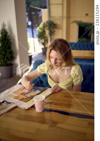 a beautiful young artist in a yellow dress paints a customized shopping bag a beautiful young artist in a yellow dress paints a customized shopping bag 116115294