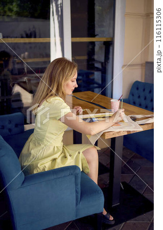 a beautiful young artist in a yellow dress paints a customized shopping bag 116115306