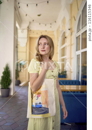 beautiful young artist in yellow dress posing with hand painted customized shopping bag 116115346