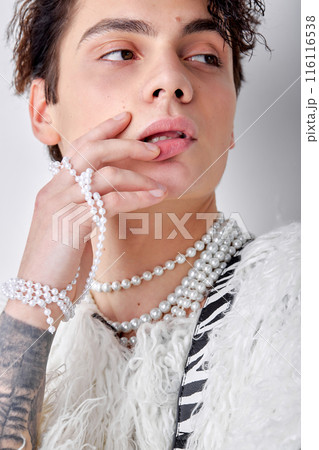 Close-up man with dark wavy hair, in necklace and fluffy jacket looking at side posing Close-up man with dark wavy hair, in necklace and fluffy jacket looking at side posing 116116538