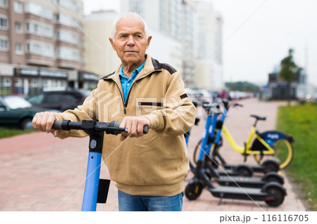 Portrait of elderly man with electric scooter on street 116116705